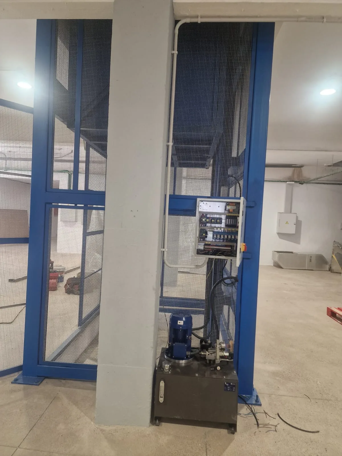 Montacargas instalado junto a una columna, con el grupo hidráulico y el cuadro de maniobra
