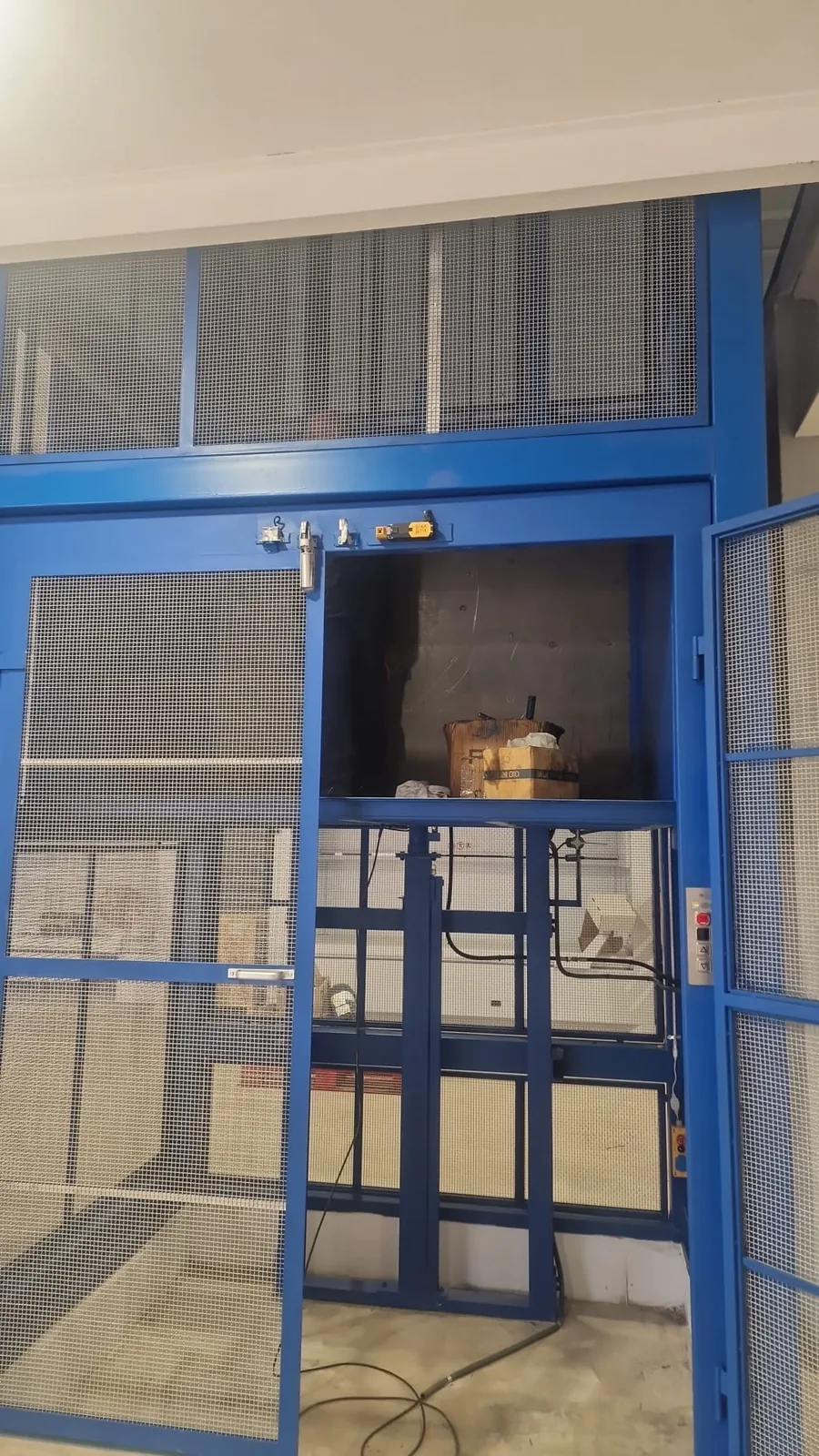 Montacargas de malla azul con cajas sobre la plataforma