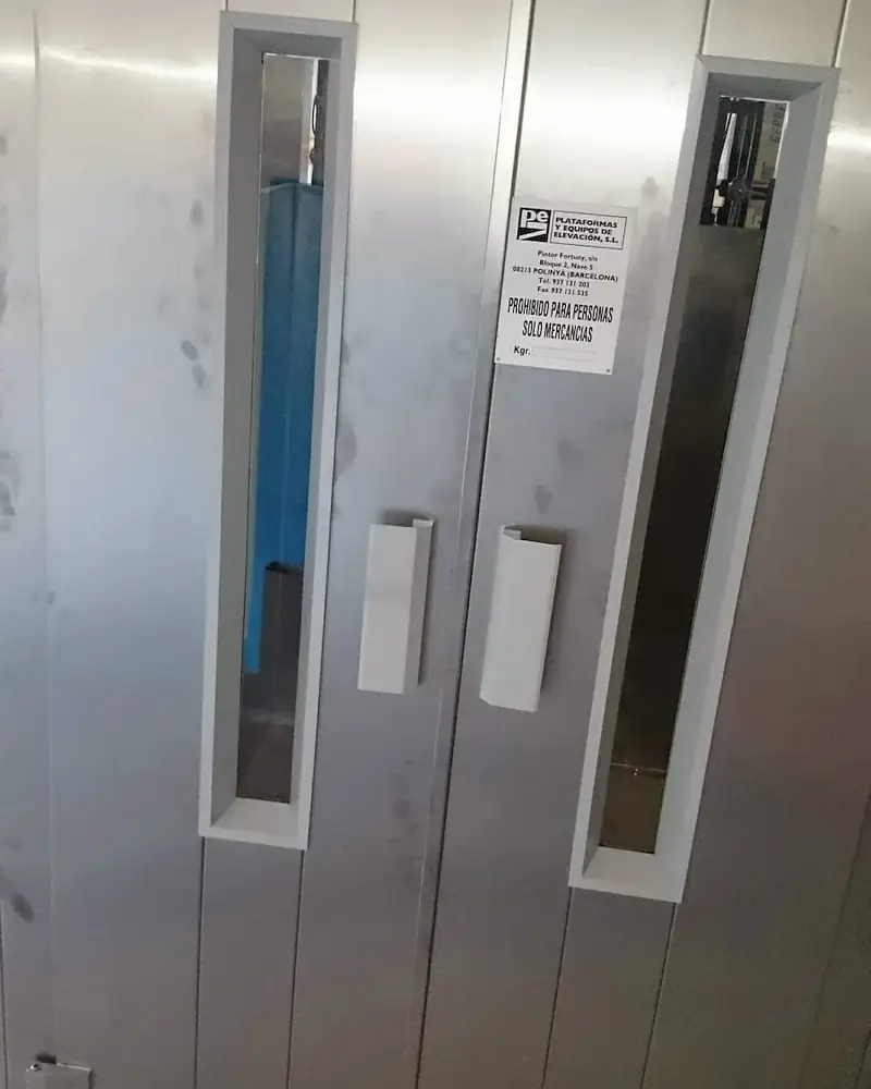 Puertas de un equipo de elevación de mercancías instalado en un paramento, con la placa de características de la empresa