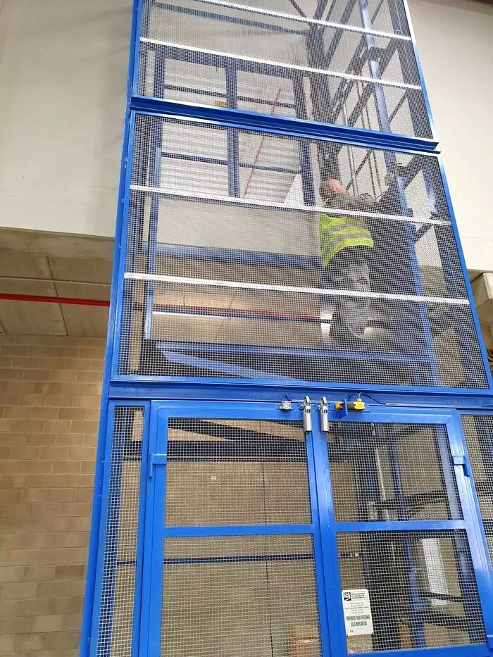 Técnico revisando el cerramiento de malla de un montacargas